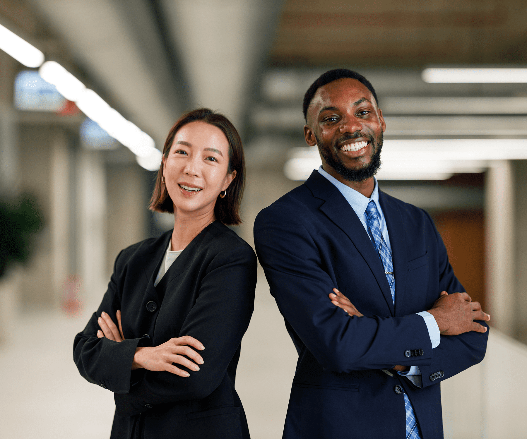 Two confident business professionals standing back to back with arms crossed.