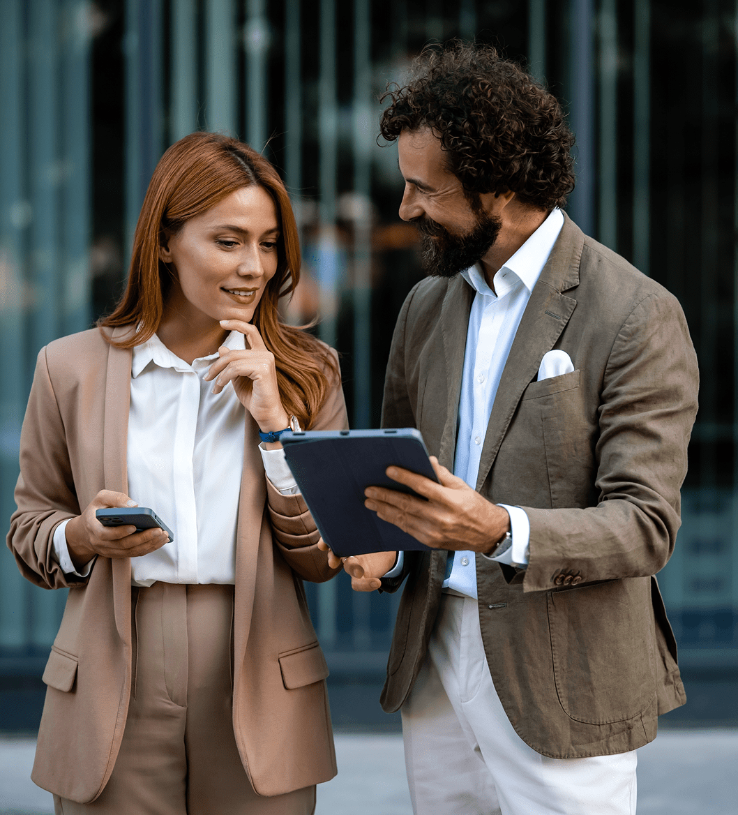 Two professionals discussing work on a tablet outdoors.